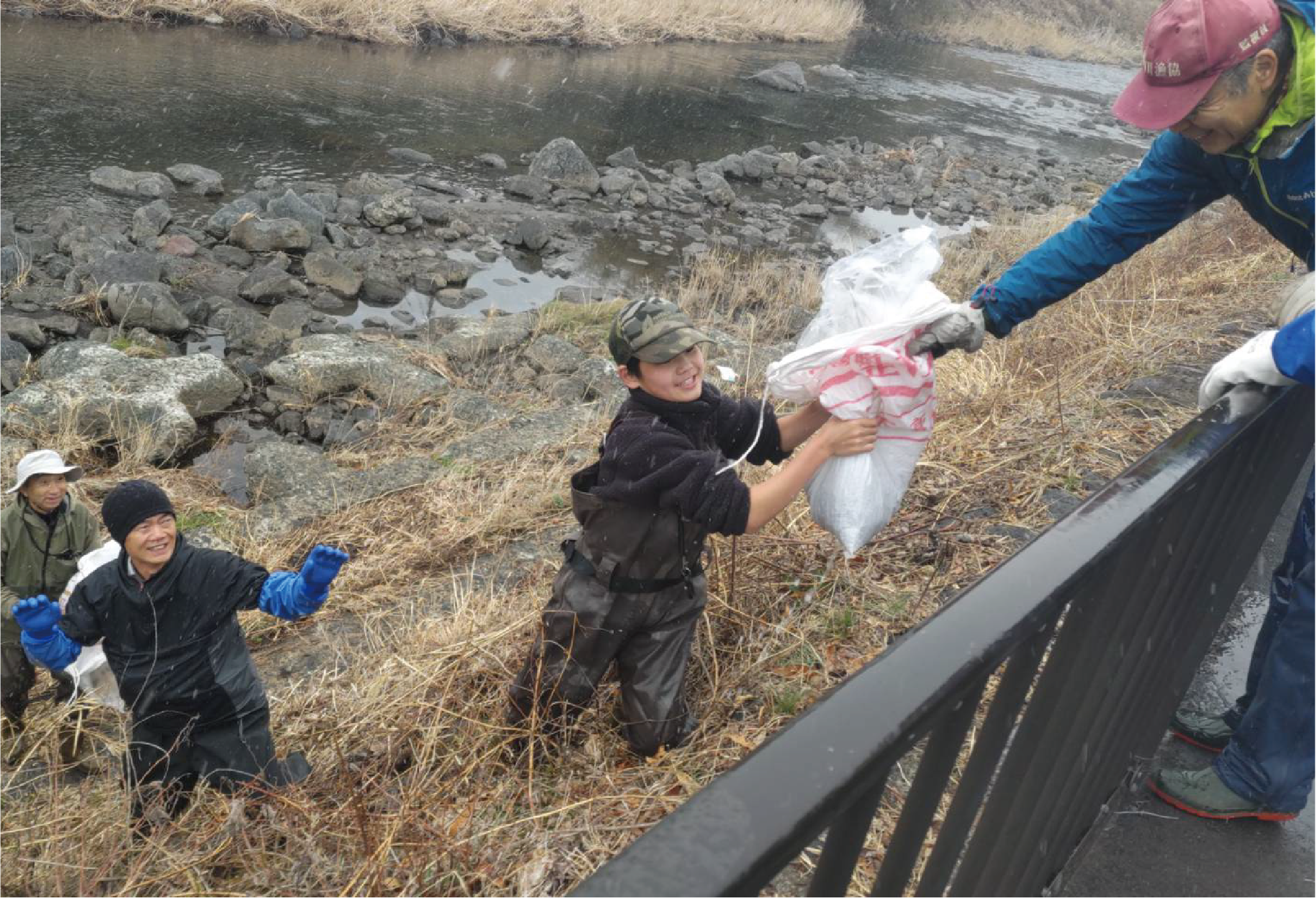 雪の中、川にあまごを運ぶ様子